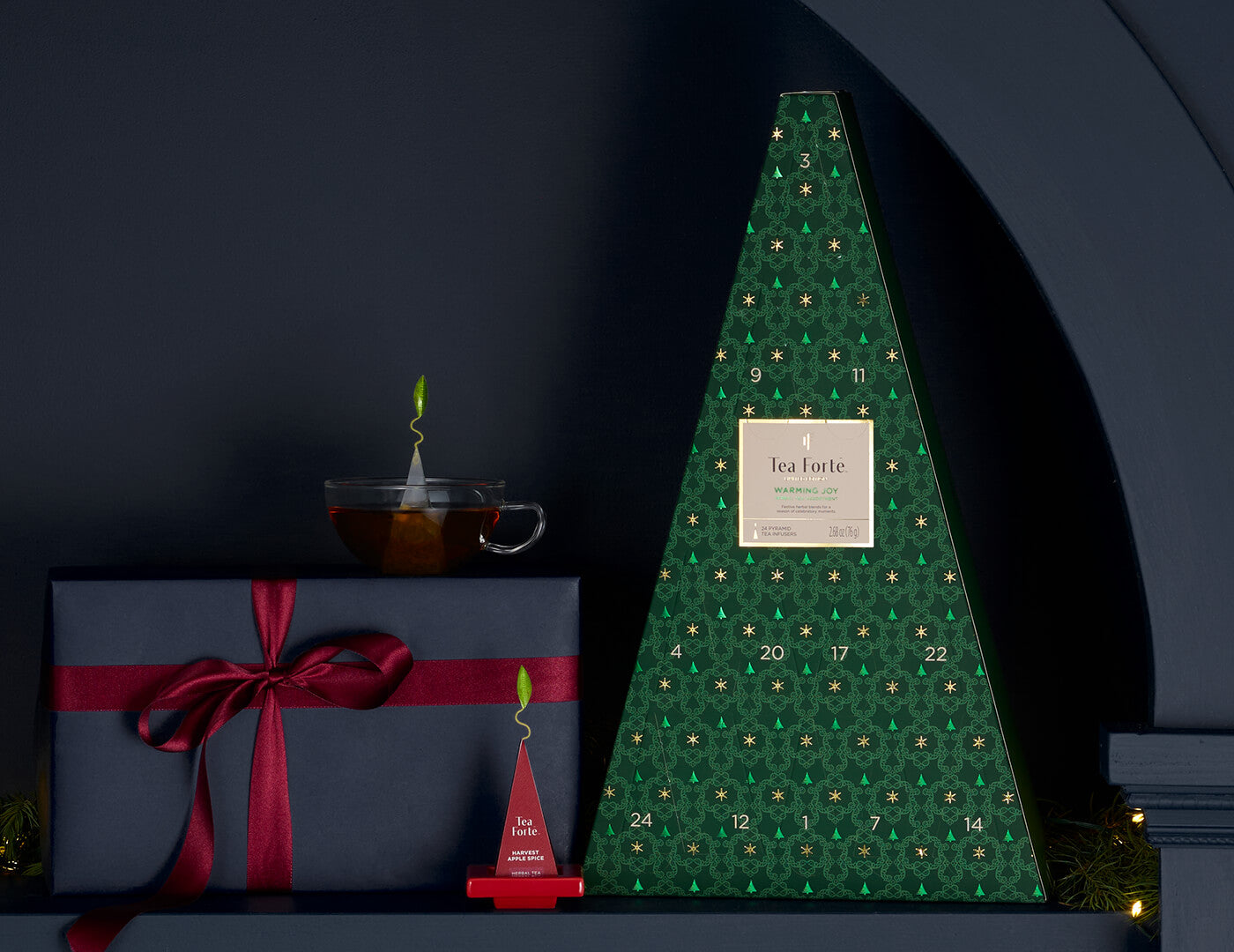 Warming Joy Herbal Advent Calendar with tea tray, cup of tea and presents on a shelf