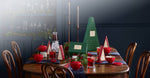 Dining table set for Christmas with decorative Advent trees and red teacups.